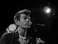 A man sings intently into a microphone.