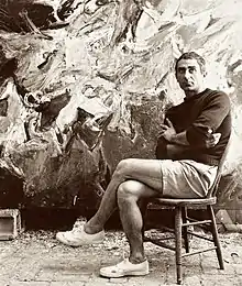 Nicolas Carone, sitting in his studio in East Hampton, NY, in the late 1950s, with his painting Nuptial Waters, 1957, behind him