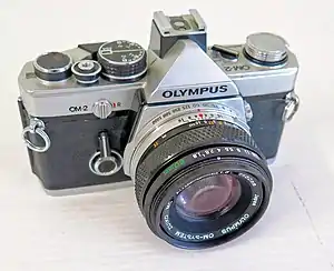 Olympus The 35&nbsp;mm film-based Olympus OM-2 (1975), which was the first SLR to measure light for electronic flash off the film plane.