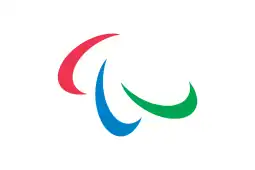 A flag with three red, green, and blue swooshes on a white background. It is attached to a flagpole and is framed by a blue sky