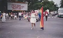 image of parade with individuals holding rainbow colored pride flags in El Salvador