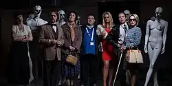 An assortment of characters and mannequins in a darkened room