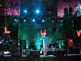 R.E.M. performing on stage with a sign reading "LUV" behind them