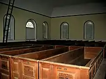 Straight-backed, carved, pews and crude ladder to loft
