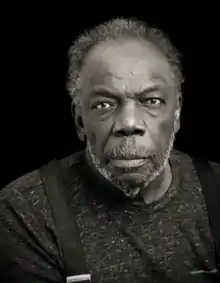 Black man with mustache and beard looking directly into the camera