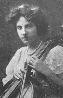 A young white woman holding a cello and bow.