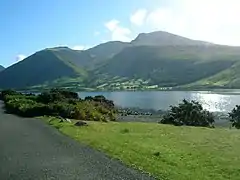 Lush hills beyond a long, narrow lake.