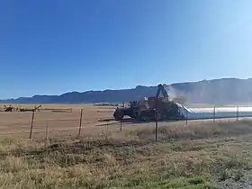Two tractors deploying a sealed storage method for a harvest