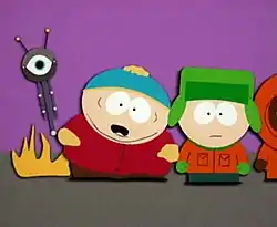 A crudely animated cartoon image of an obese child with a red jacket, brown pants, black shoes and a blue hat. Flames appear from the rear of his body, as well as a tall vertically shaped machine with a single eye and two antennae. Standing next to him is another boy wearing an orange jacket, green pants, brown shoes, a green hat and gloves.