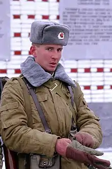 Russian soldier shortly after the dissolution of the Soviet Union wearing the formal and closed setup of the ushanka with the winter version of the Afghanka; both the Afghanka collar and the ushanka are made from fish fur (January 1992)