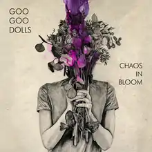 An art piece in beige with a woman holding flowers in front of her face that are purple