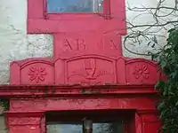 A view of the marriage stone lintel positioned over the entrance to 'The Hill' farm mansion house together with the motto "Delights and Adorns" and a Bible held in a hand dexter held upright, suggesting both northern Ireland and Protestantism.