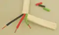 Broad white-coated cable, cut away to show green, red and black coated wires