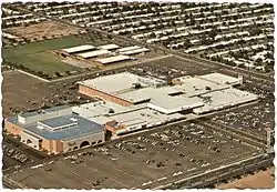 An aerial image of Tri-City Mall in Mesa, Arizona, showing the mall structure and its surrounding parking lot.