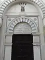 A mausoleum door, topped by a commemorative inscription.