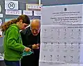 Poster at a polling station in Israel, with party symbols explained in Arabic and Russian.
