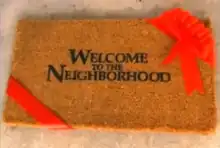Title card with the series' name in black letters on a brown mat; the mat has a red ribbon wrapped around two of its ends