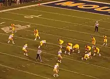 American football players line up for a play in a full stadium.