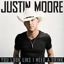 The cover has the artist in the center of a white background, wearing a black t-shirt and white cowboy hat with a black ring around it. Above the artist is his name boldly colored in black, and below him is the song title colored in teal against a black background.