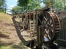 A wooden water wheel with water flowing over it.